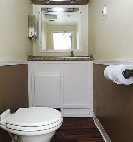 Side view of three station restroom trailer with three separate doors with signs