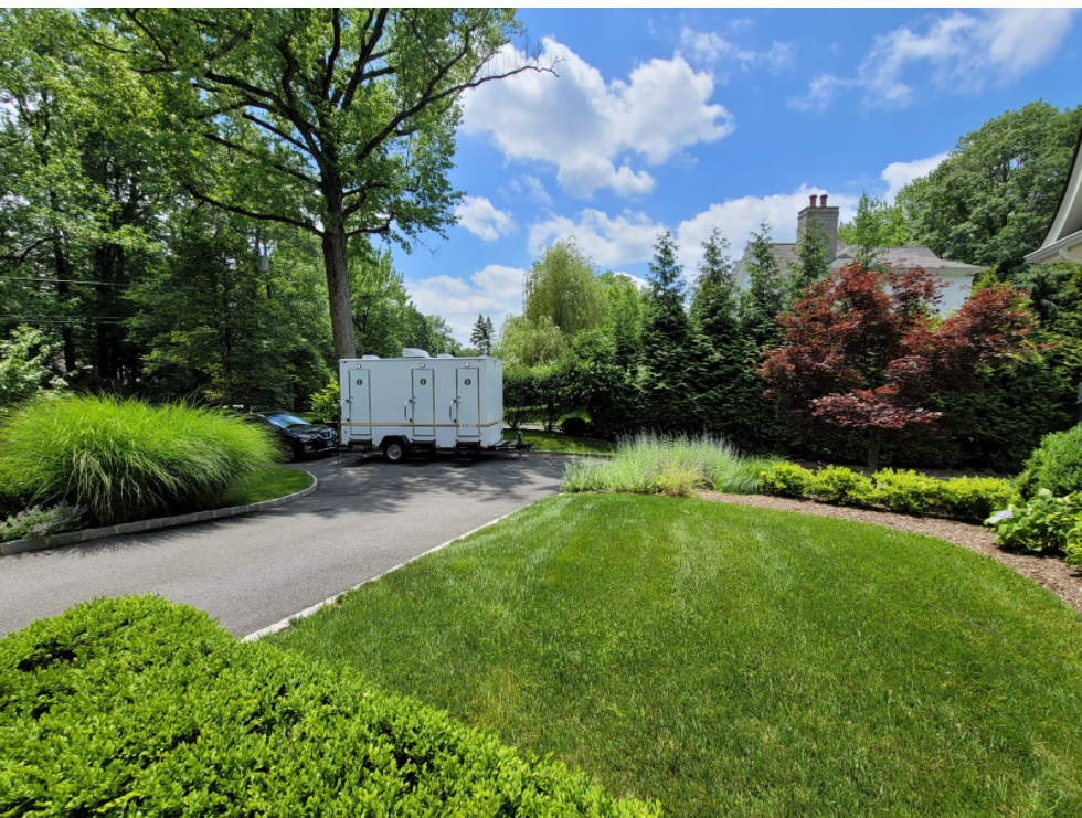 Restroom trailer surrounded by greenery and trees