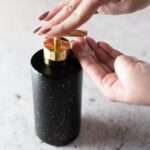 Woman using a sanitizer from a marble counter